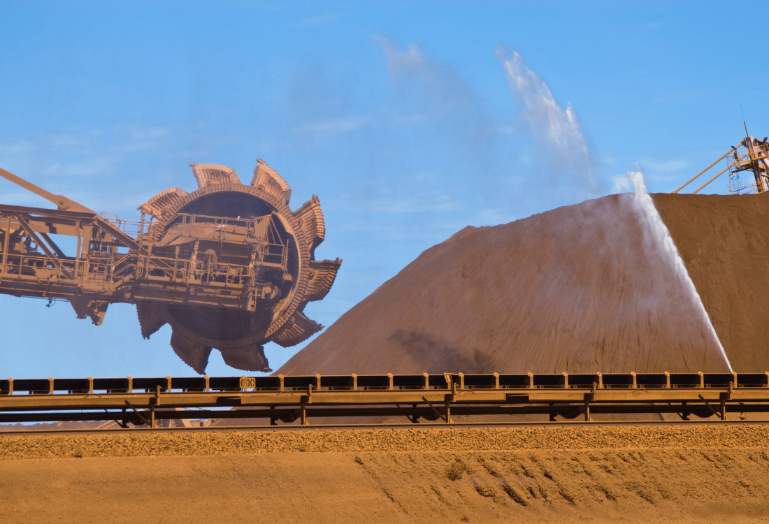 Spray treatment being applied over an ore stockpile