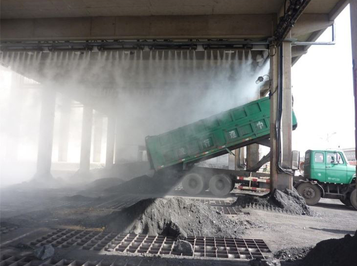 Open truck handling dusty bulk material under spray
